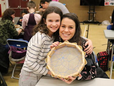 Female student poses with her mother showing the hand drum the student has created