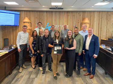 The board and the recipients of an awards stand in front of Abbotsford SD logo holding awards